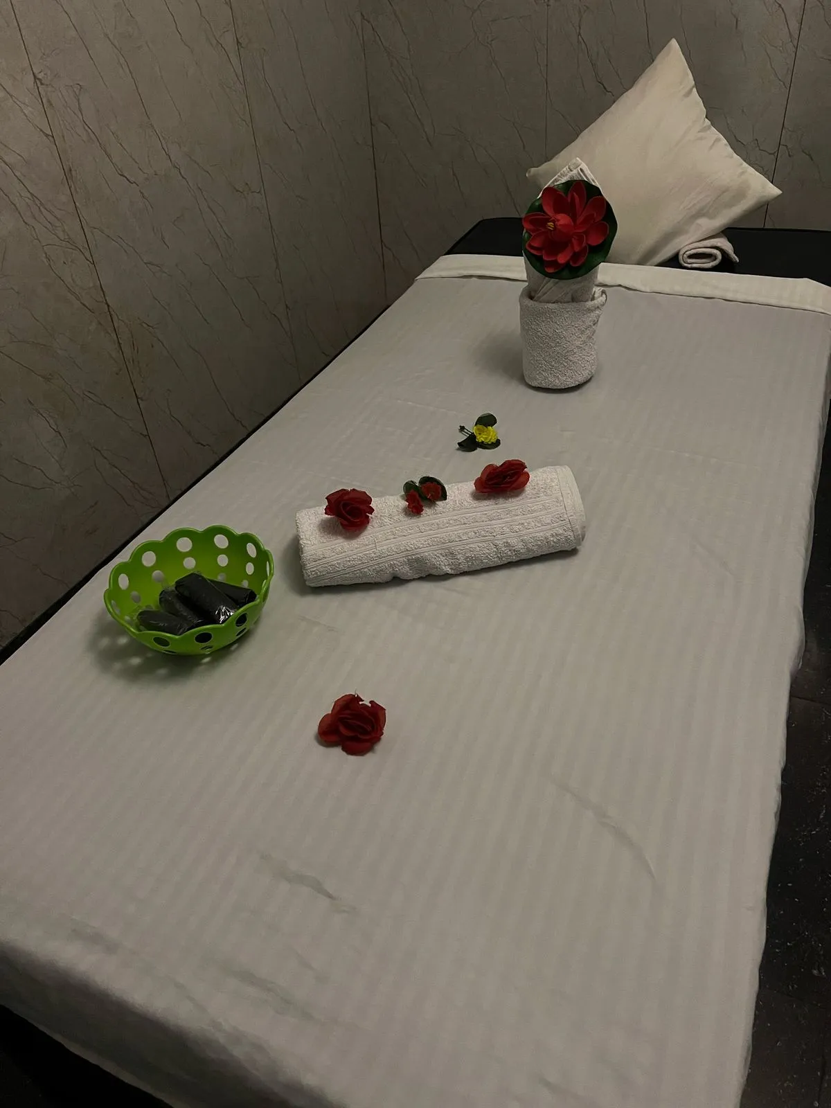 A treatment bed at Green Spa Pokhara — fresh white linens, a single rose and a small green bowl of warm stones