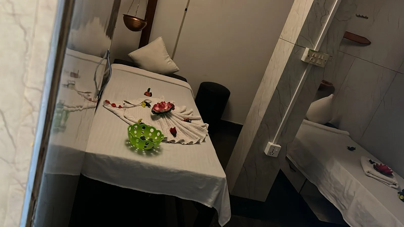 Twin treatment rooms set up for a couples massage with white linens and lotus flowers